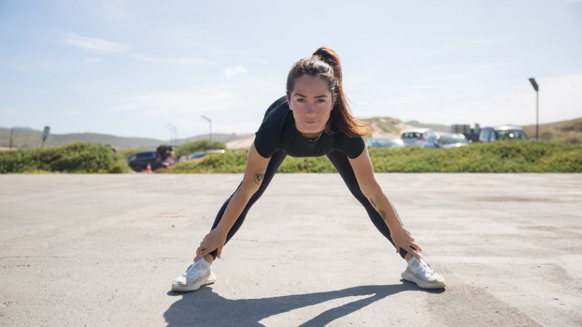 A woman in activewear stretching outdoors in a sunny Portuguese landscape, embracing a healthy lifestyle.