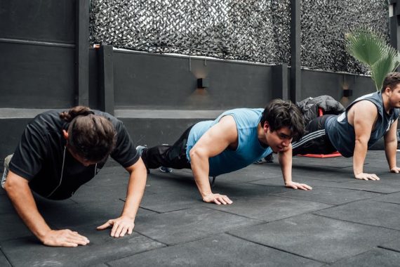 Men performing push-ups during a group workout session in Mexico City gym.